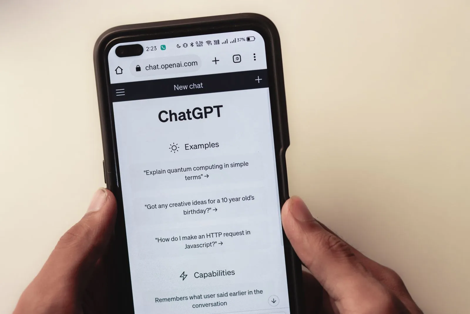 Hands holding a phone with the ChatGPT welcome screen open in a mobile browser