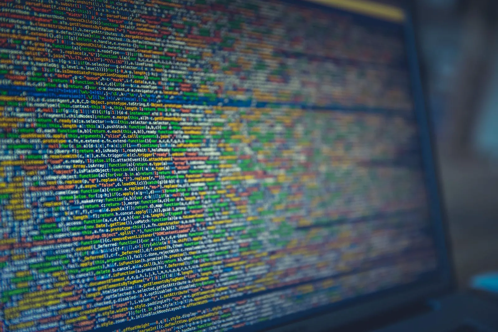 Extreme close-up of a monitor showing blurred, colorful jQuery source code