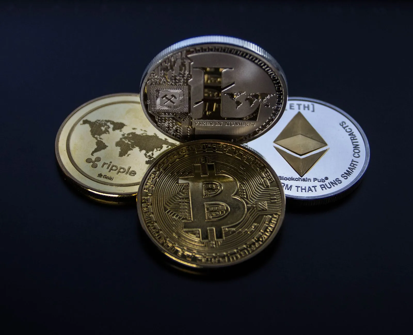 Physical Bitcoin, Ethereum, Litecoin, and Ripple commemorative coins stacked together