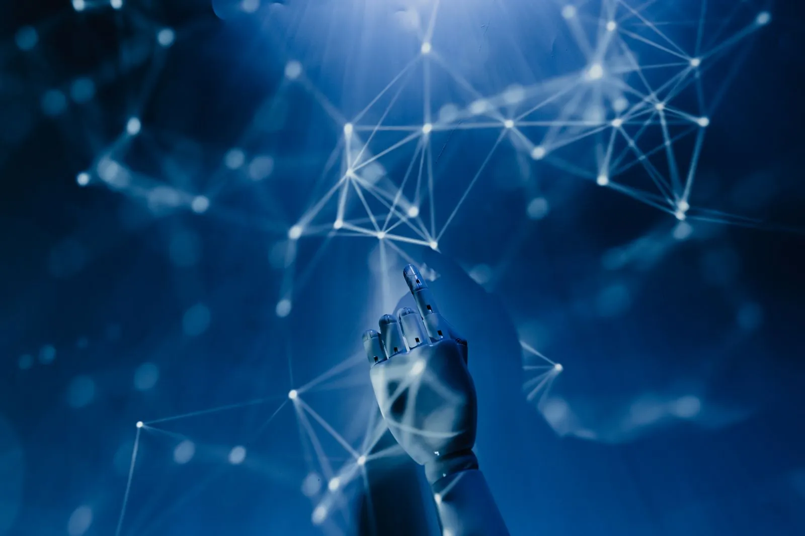 Robotic hand reaching toward a glowing network of connected nodes