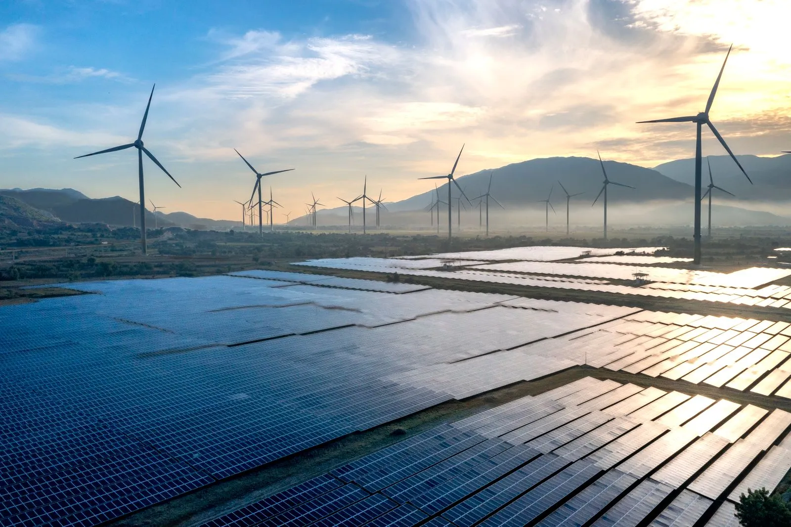 Wind turbines and solar panels at sunset