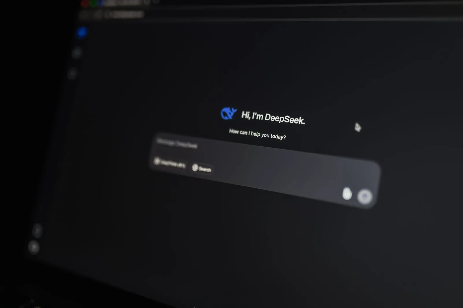 Blurred, angled monitor shot of DeepSeek AI's welcome screen with a cursor near the greeting