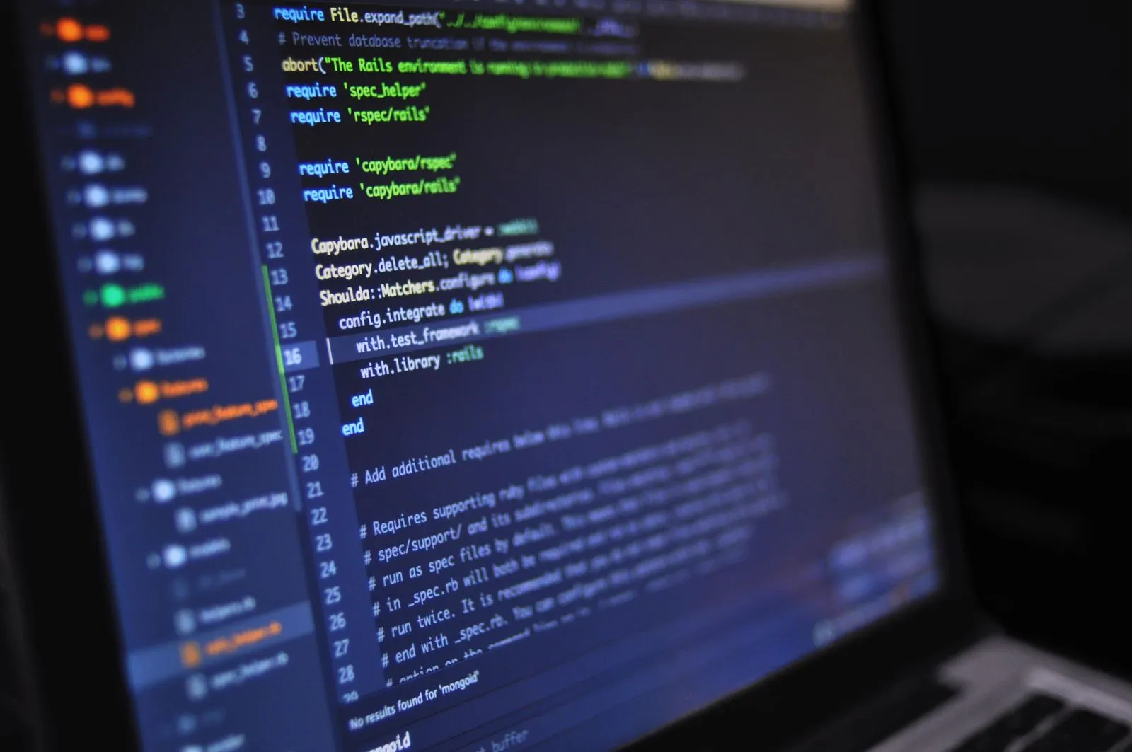Close-up of a laptop screen showing Ruby RSpec and Capybara test configuration code