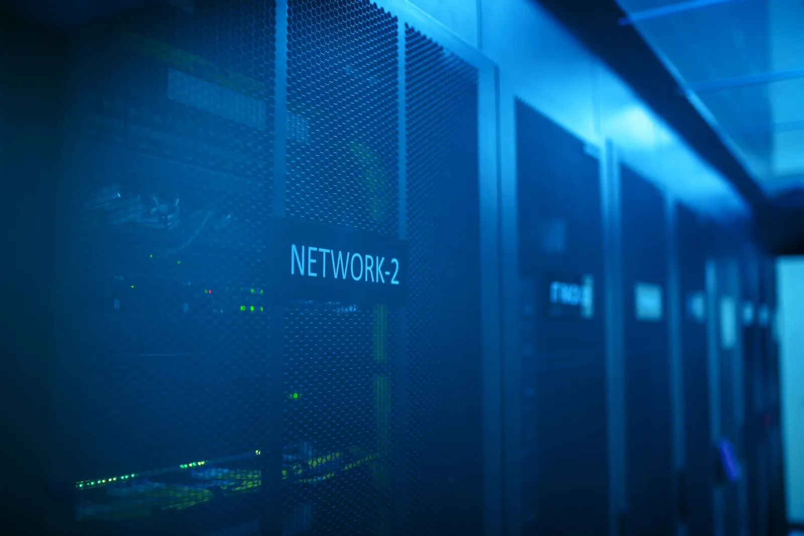 Blue-lit data center aisle with a 'NETWORK-2' label sign on a server rack