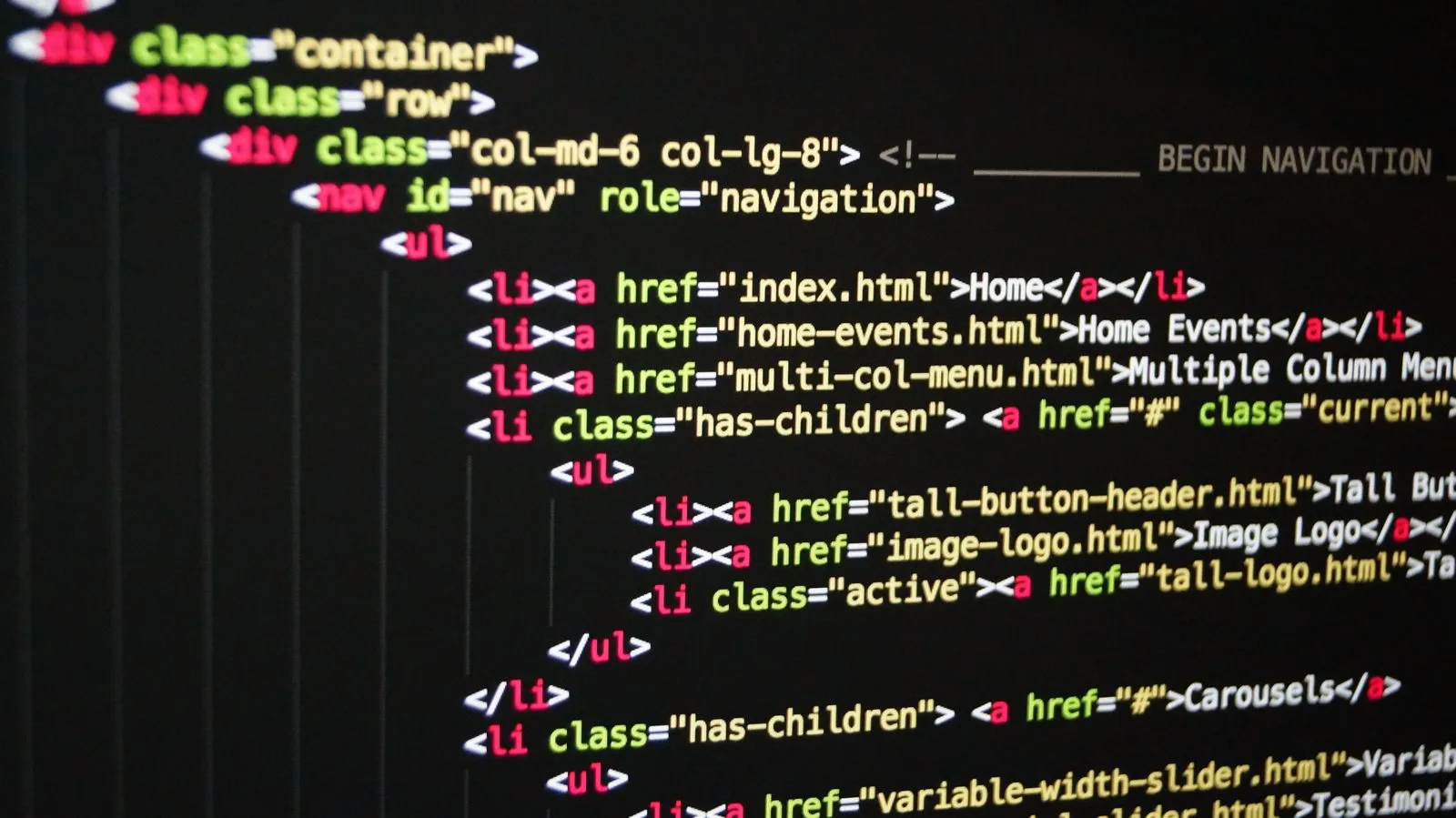 Close-up of a monitor showing HTML navigation markup with Bootstrap-style CSS classes