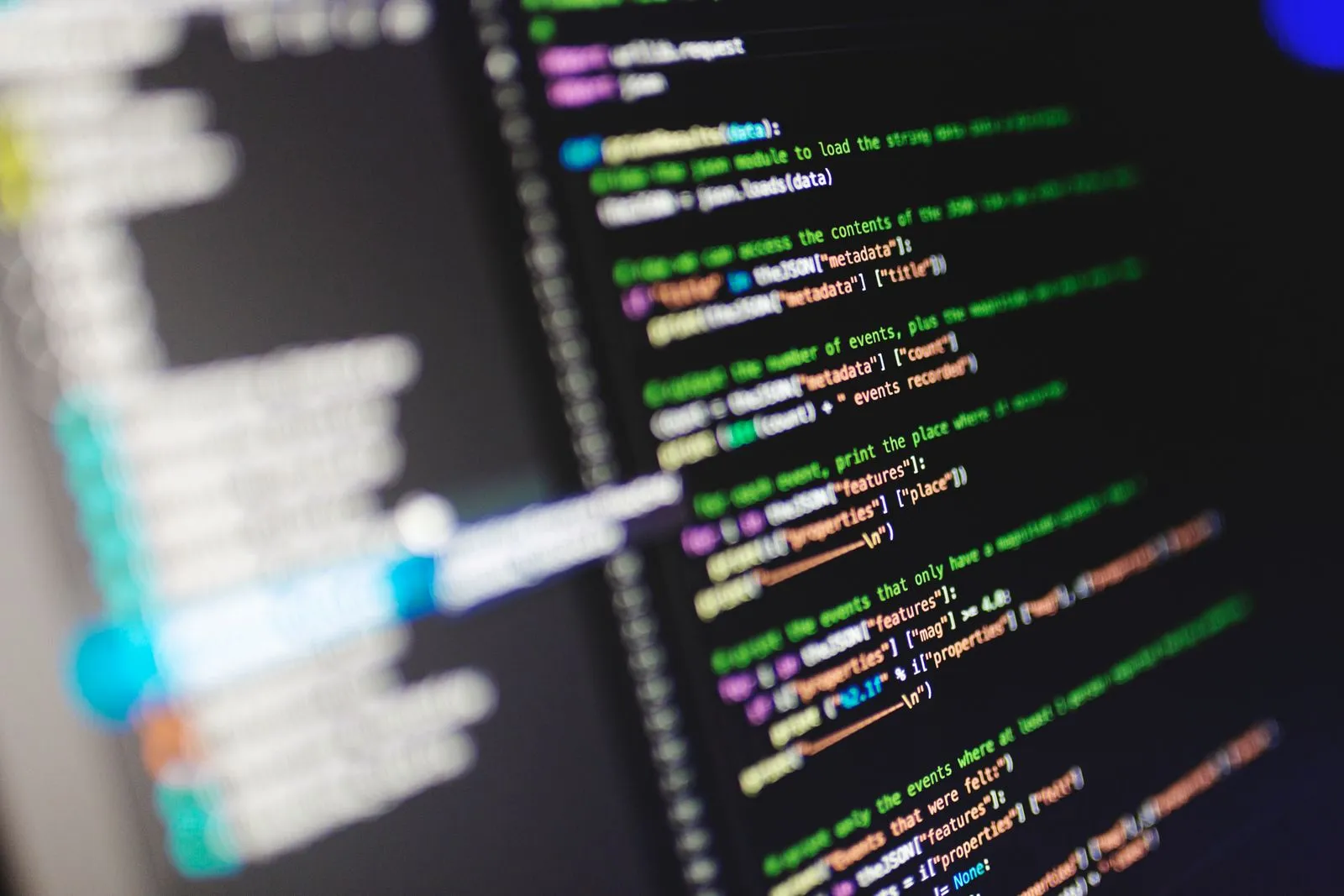 Blurred Python code parsing JSON event data, with a stylus resting near the screen